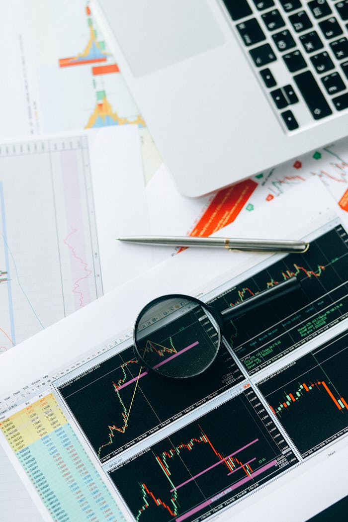Magnifying glass and graphs depicting stock market data analysis on paper documents.